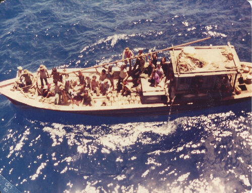 A still from the film 'Finding The Virgo' featuring an aerial view of multiple people standing on a wooden boat