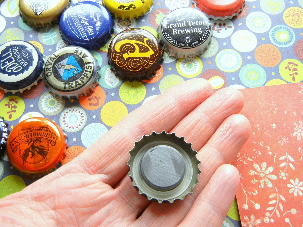 A hand holding assorted bottle cap magnets 