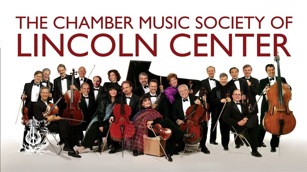 The Chamber Music Society Of Lincoln Center smile and pose with their instruments in front of a white background