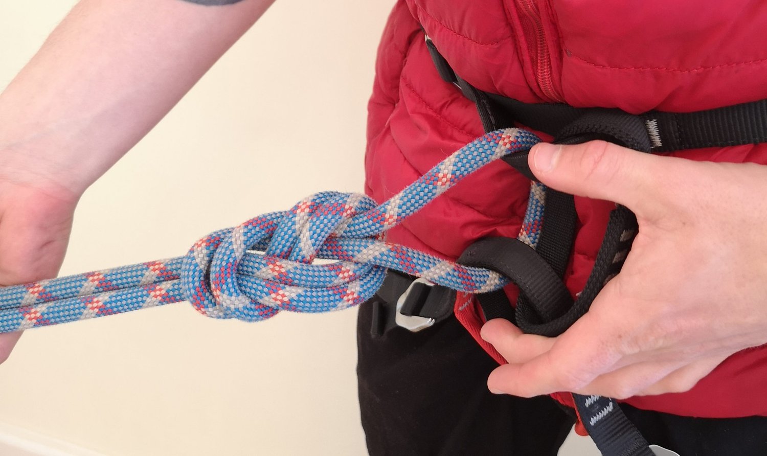 Someone tying a rope onto their rock climbing belay harness