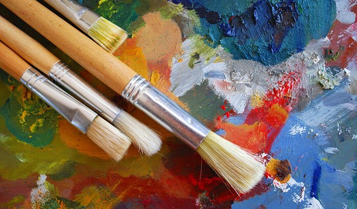 Paintbrushes lying on top of a multicolored painted surface 
