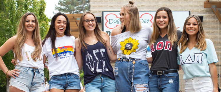 A line of six sorority members smiling and posing in the Student Center Plaza
