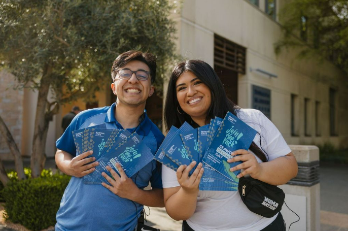 People smiling and posing with fanned out Decision Day programs
