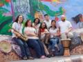 The seven members of Lior Ben Hur smiling and posing with their instruments in front of a colorful mural