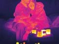 The 'Atlantis' film poster featuring a thermal image of two people embracing on another on a bed with coffee mugs on a surface in front of them