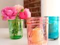 Three colored Mason jars with flowers and candles inside of them