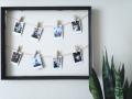 A wall frame with strings and clips holding polaroid photos