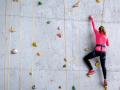 Someone wearing athletic clothing climbing an indoor rock wall 