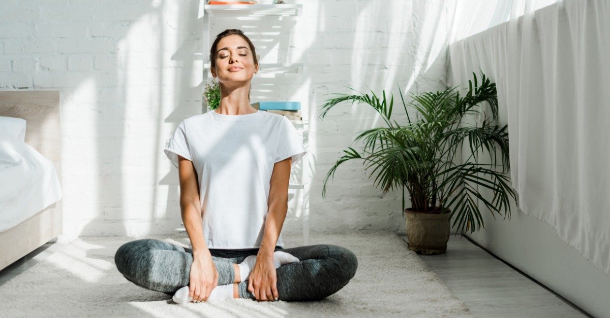 Someone smiling while in a seated yoga pose in an indoor setting