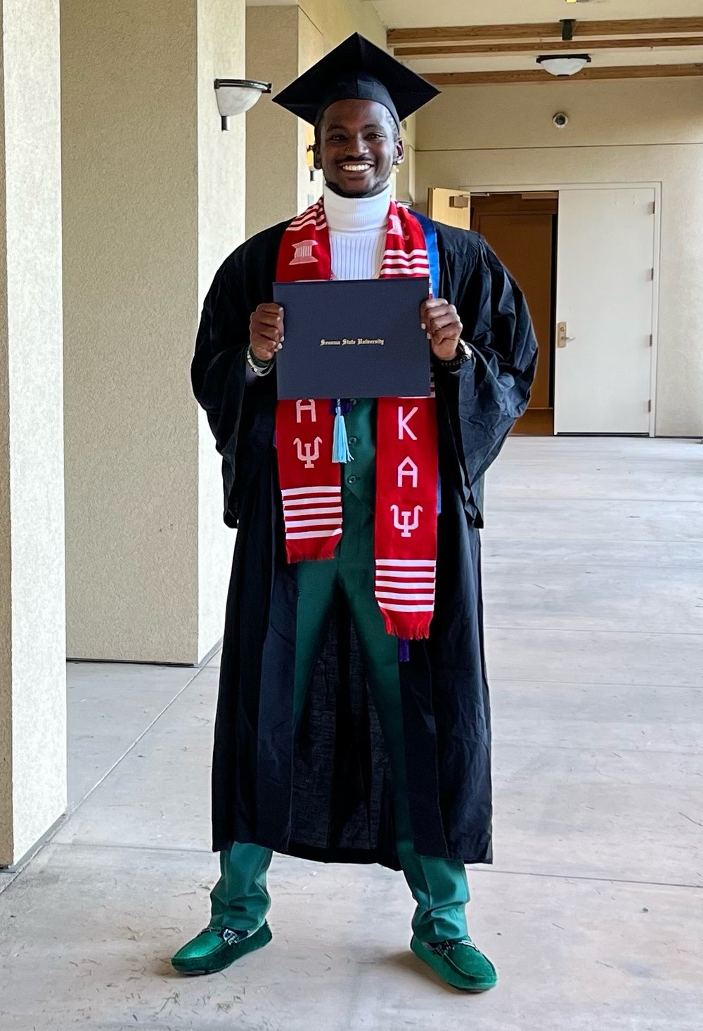 A student smiling and posing with their diploma at Black Graduation