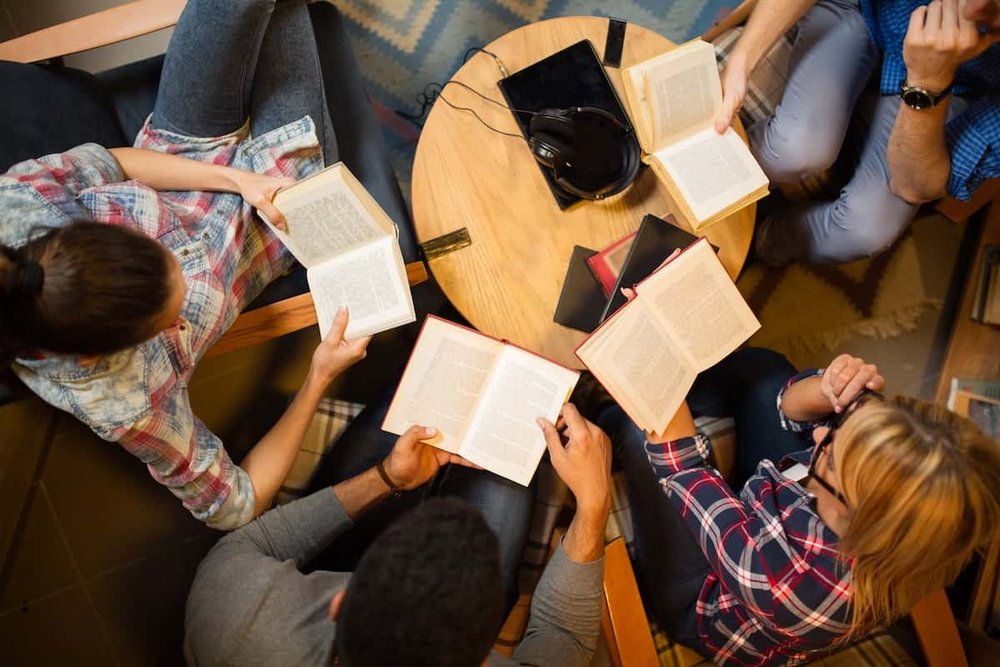An above-view of a group of people reading books together 