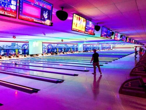Someone bowling in a neon-illuminated bowling alley 