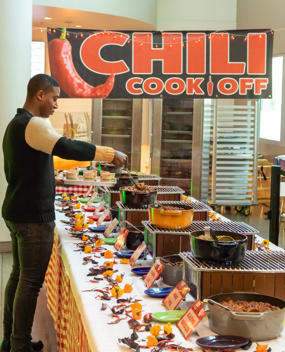 A student scooping chili at the Kitchen's Chili Cook Off