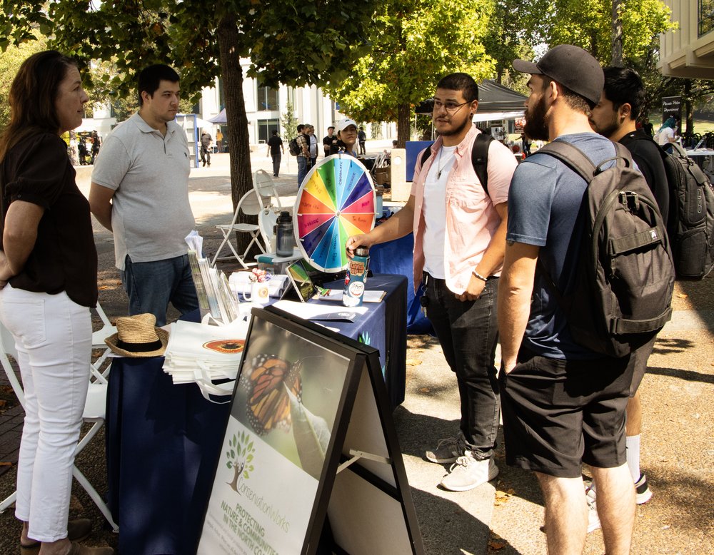 People chatting while tabling at an outdoor job fair