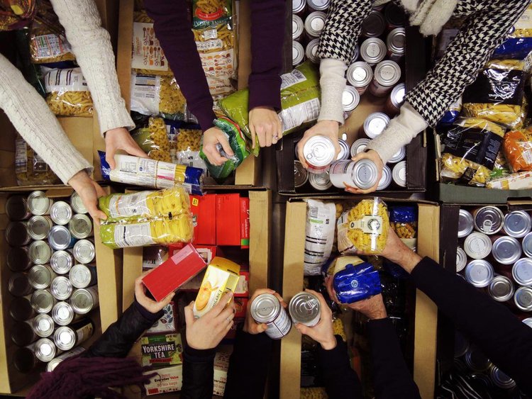 A group of people holding different food items at a food bank