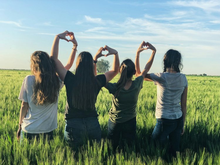 A group of friends posing together with heart hand gestures