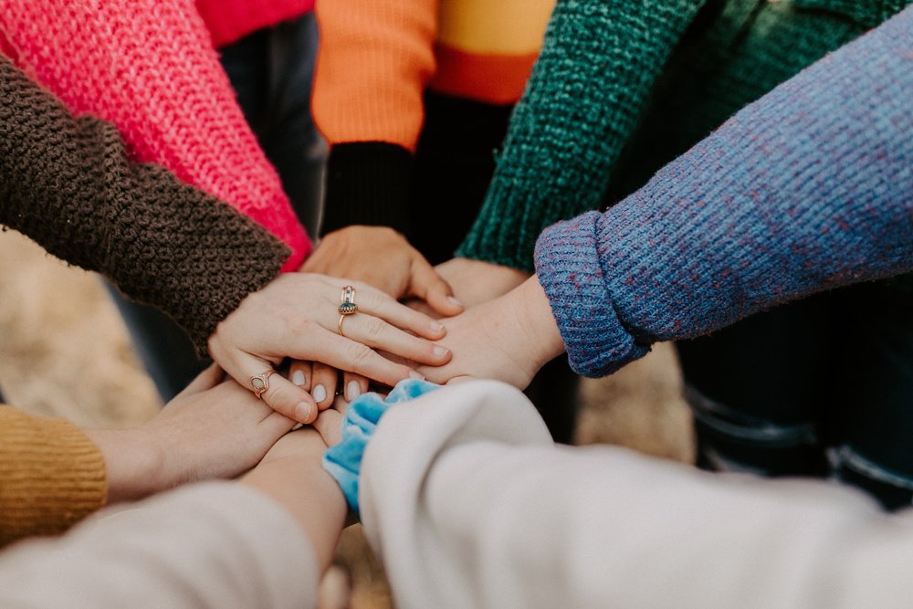 A group of people putting their hands together in a circle