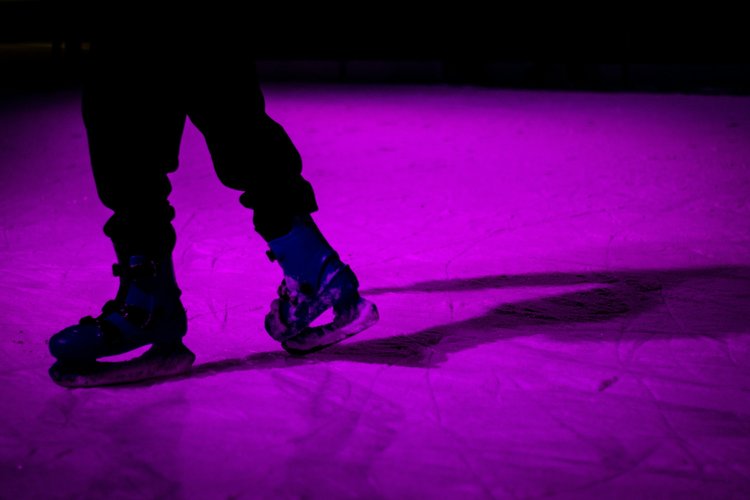 Someone ice skating in dim purple light