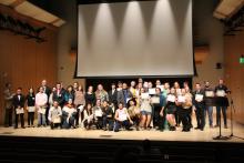 A large group of scholarship recipients posing on stage at the Scholarship Showcase