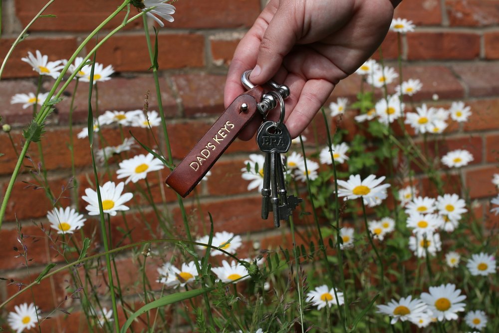 A leather keychain with the words "Dad's Key's" on it