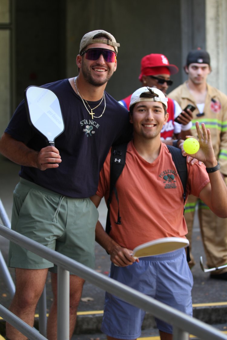 Two people posing with their pickleball equipment