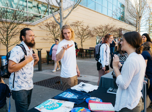 Two students speaking to someone with a recruitment fair booth at the Seawolf Plaza