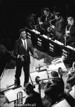 A black and white image of someone conducting an orchestra on stage