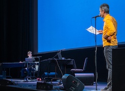 Two people performing on stage in front of a blue screen