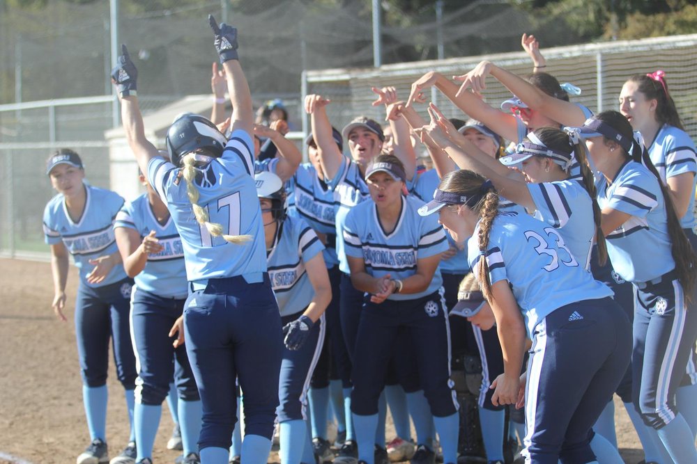 The Sonoma State softball team cheering and celebrating on the softball field 