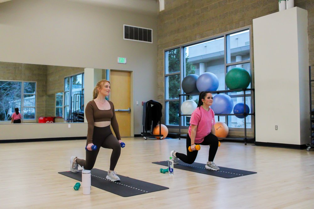 Students lifting weights while taking an exercise class at the Campus Recreation Center