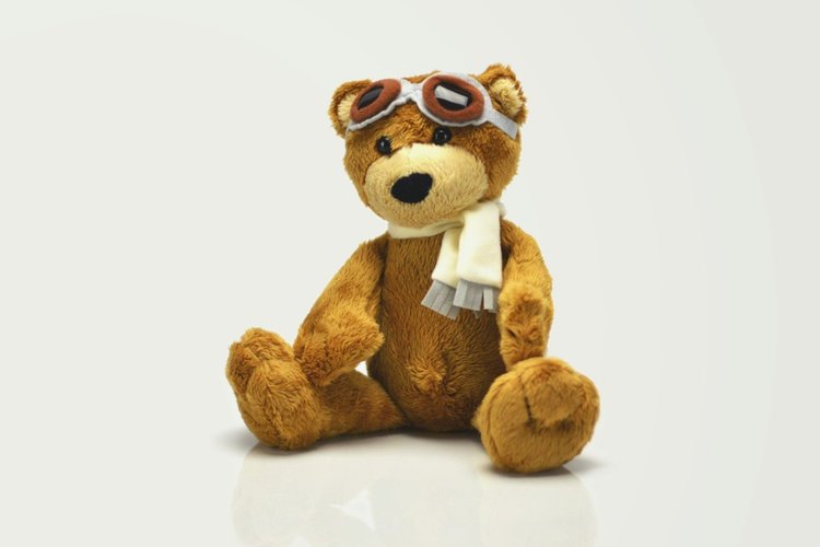 A teddy bear wearing a scarf and aviator goggles