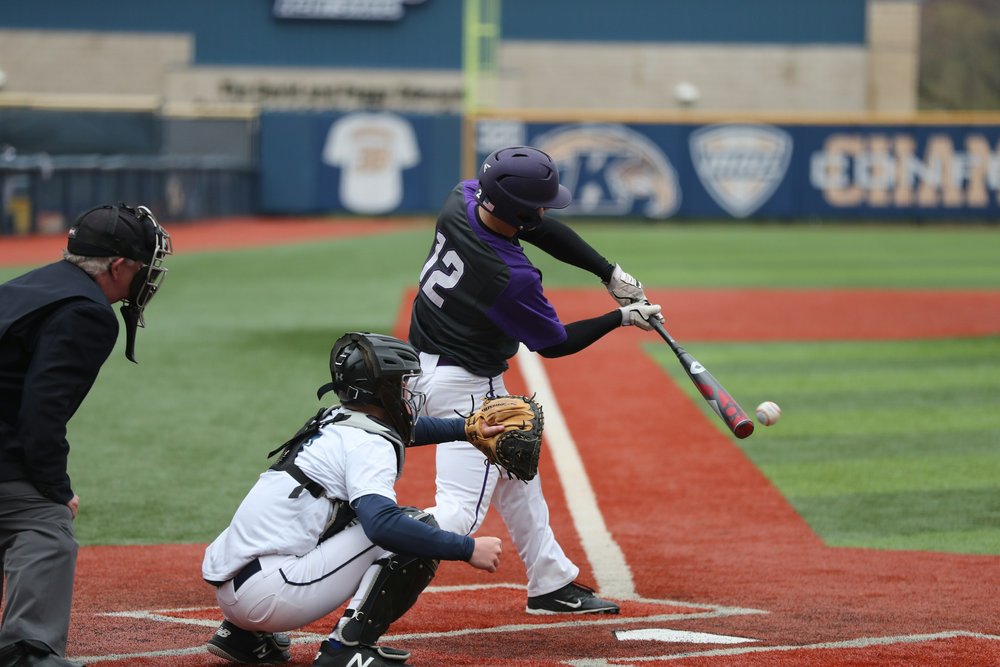 A batter swinging a baseball bat at a baseball game