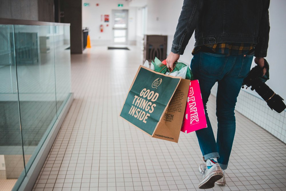 Someone walking through an indoor mall with shopping bags in their hands