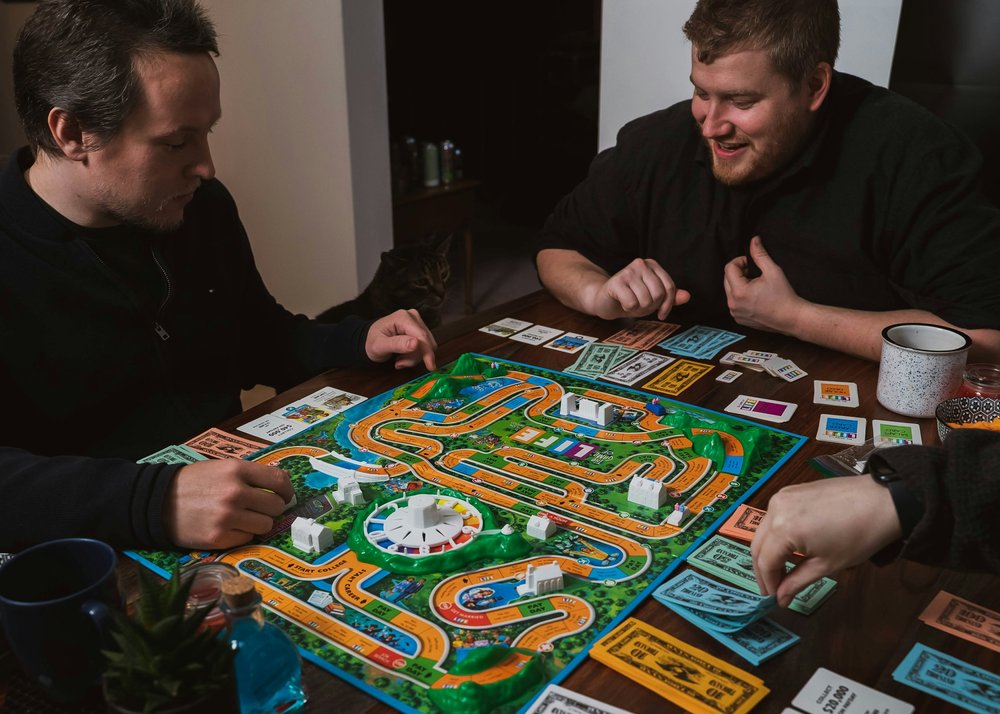 People sitting at a table laughing while playing a board game