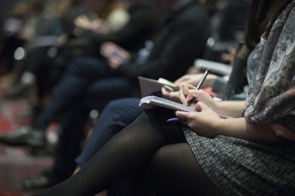 Someone writing on a note pad while sitting at a group event