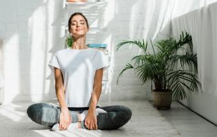 Someone smiling while in a seated yoga pose in an indoor setting