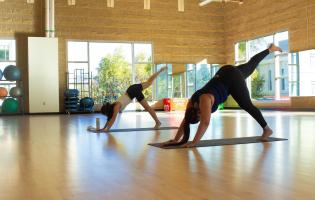 Two people doing a yoga pose inside the SSU gym