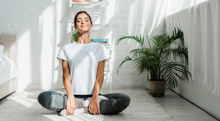 Someone smiling while in a seated yoga pose in an indoor setting