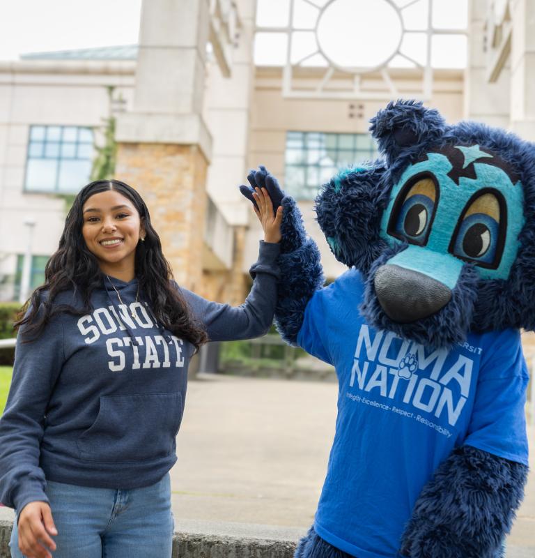 Student high fiving Lobo outside the Library
