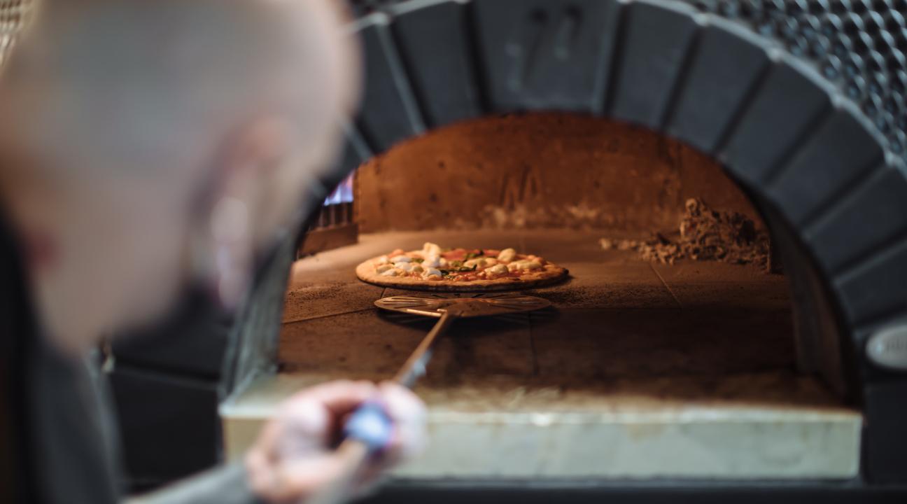 Sonoma chef pulling a pizza out of a woodfire oven