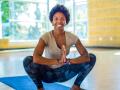 Doshia smiling while doing a yoga pose over a yoga mat