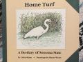 The book cover for 'Home Turf' featuring an illustration of a white crane in a marshland