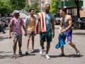 An image from the movie 'In The Heights' of four characters walking and talking on a street
