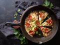 A fresh pizza inside of a cast iron pan
