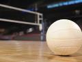 A volleyball sitting on the floor of an indoor volleyball court
