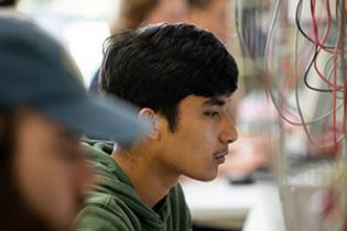 student looks closely at a bundle of colorful wires