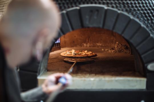 Sonoma chef pulling a pizza out of a woodfire oven